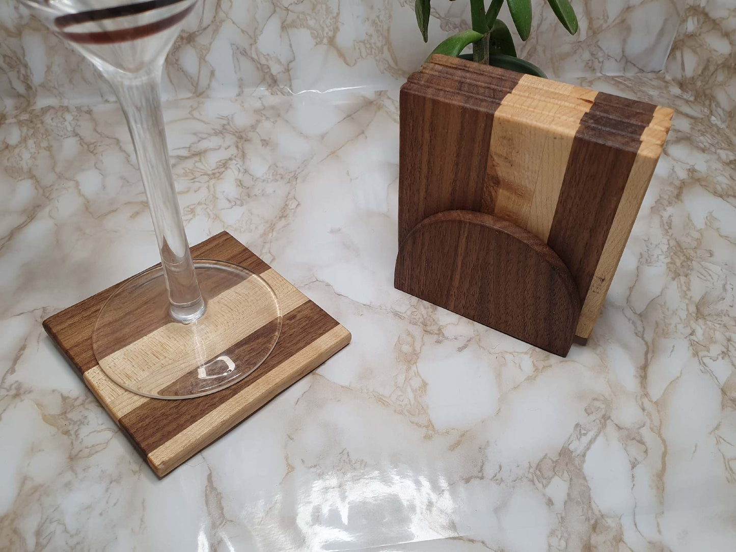 Set of 4 walnut and maple coasters with holder on a marble table.