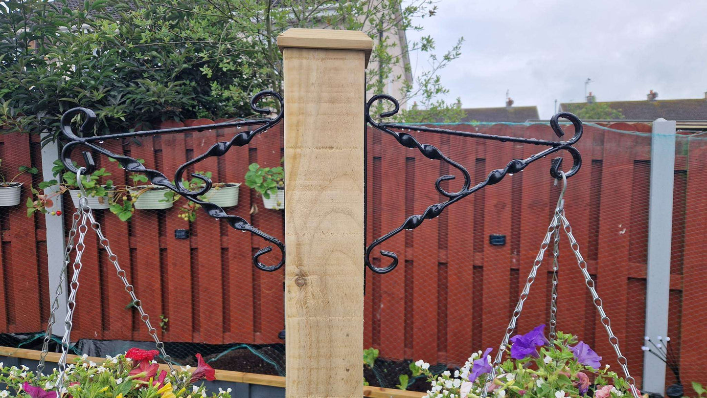 Handcrafted wooden planter with integrated hanging basket pole on a green garden lawn.