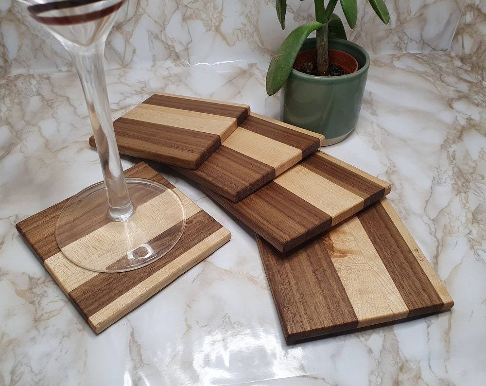 Set of 4 walnut and maple coasters with holder on marble table.