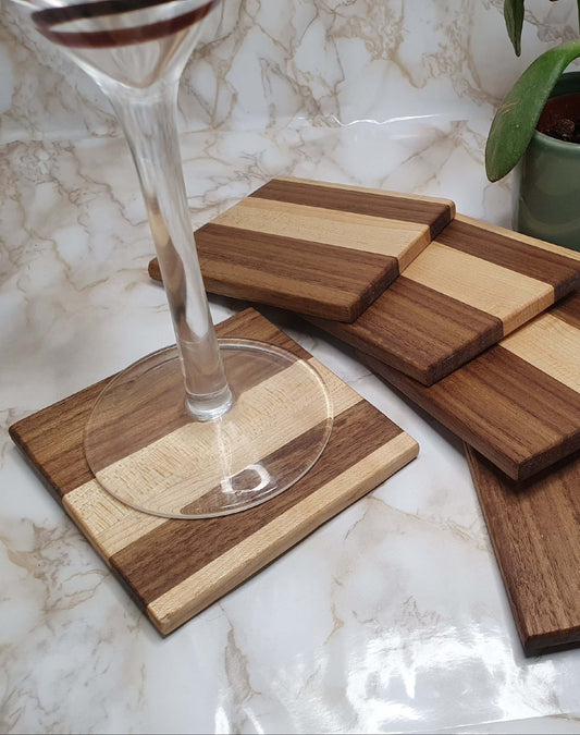 Set of 4 elegant maple and walnut coasters with holder on marble table, wine glass on top.