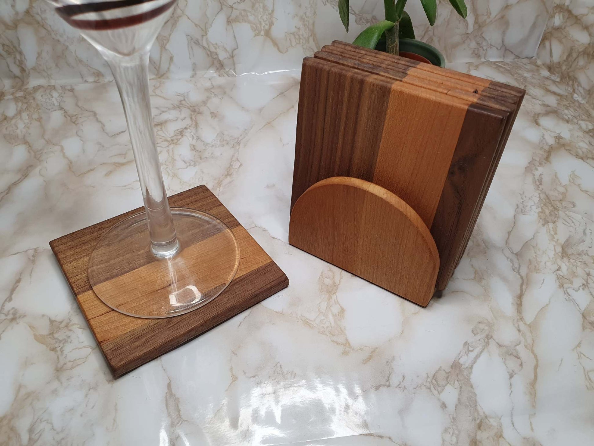 Set of 4 walnut and cherry coasters with holder on marble table.