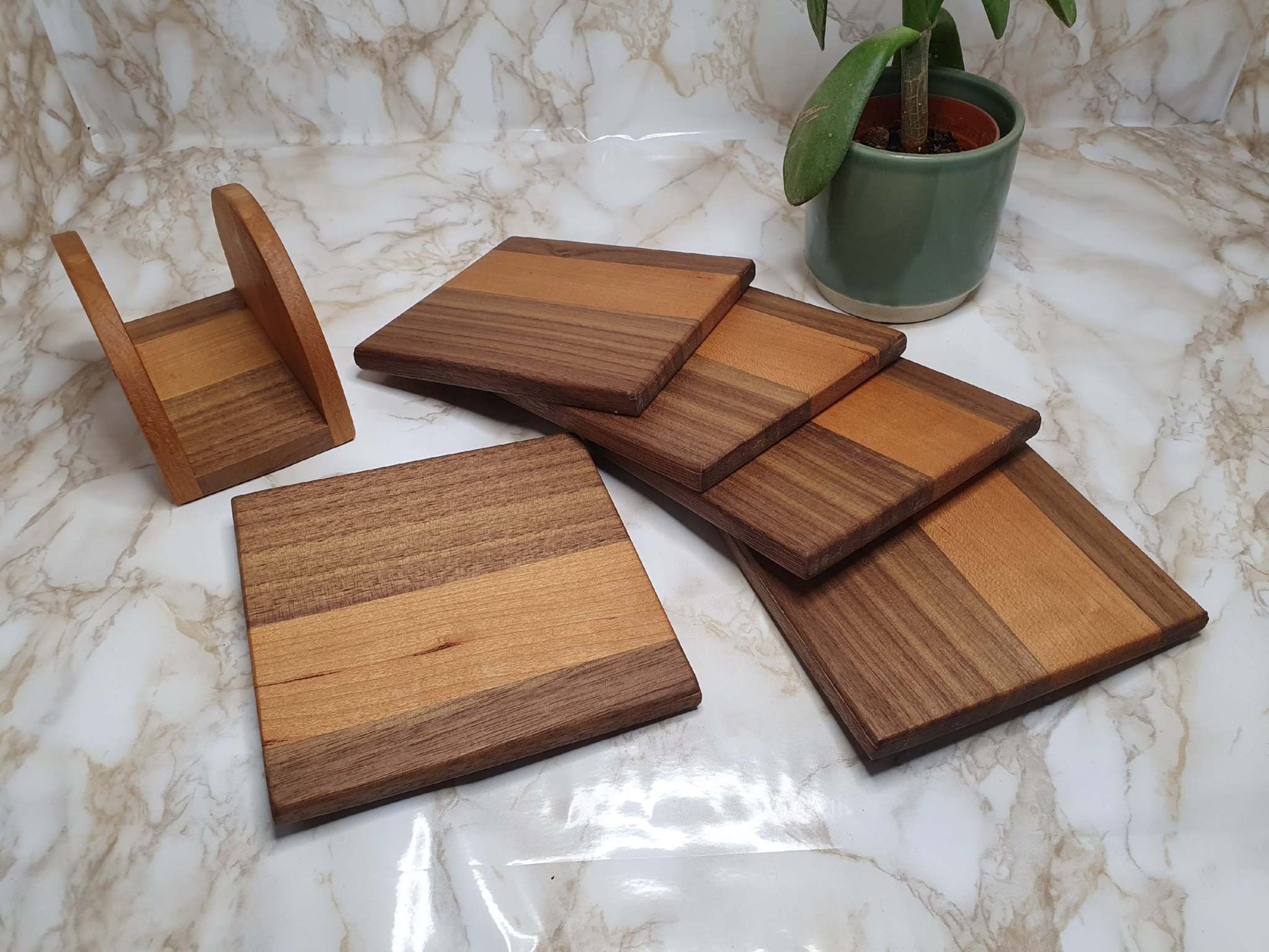 Set of 4 coasters with holder made from walnut and cherry wood displayed on a marble surface.
