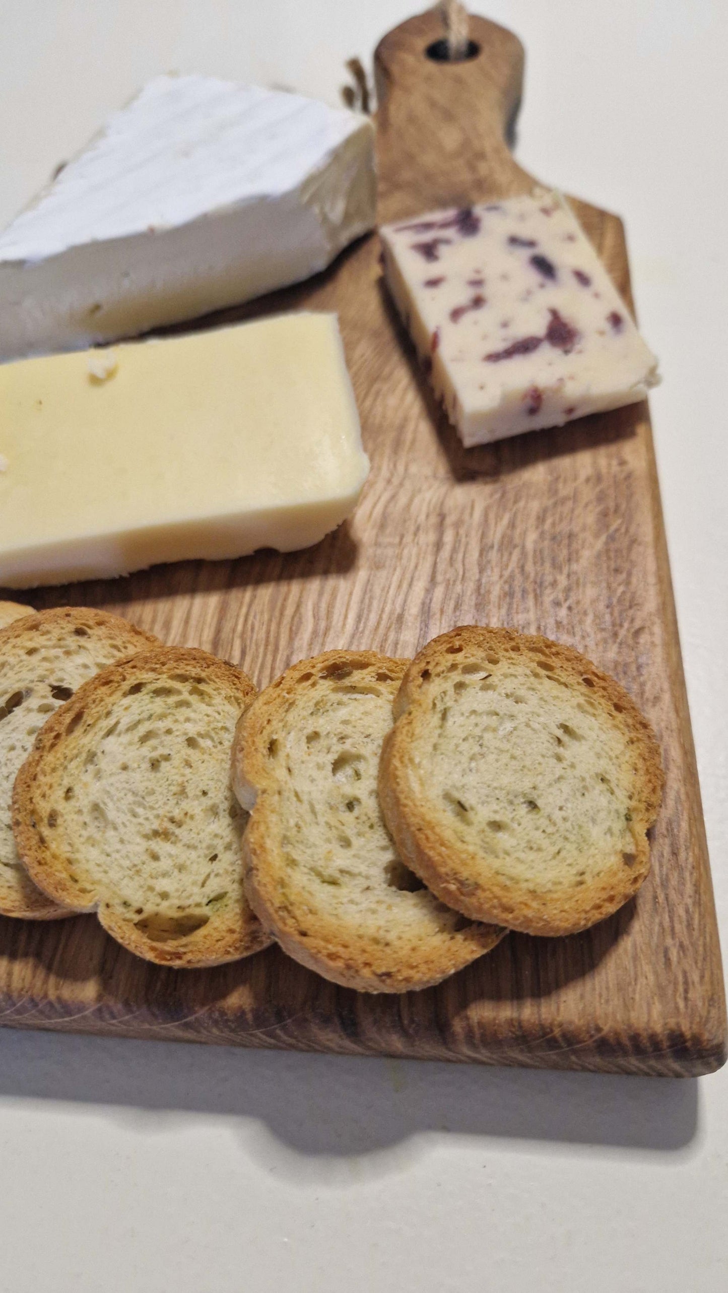 Handmade charcuterie board with assorted cheeses and bread slices.