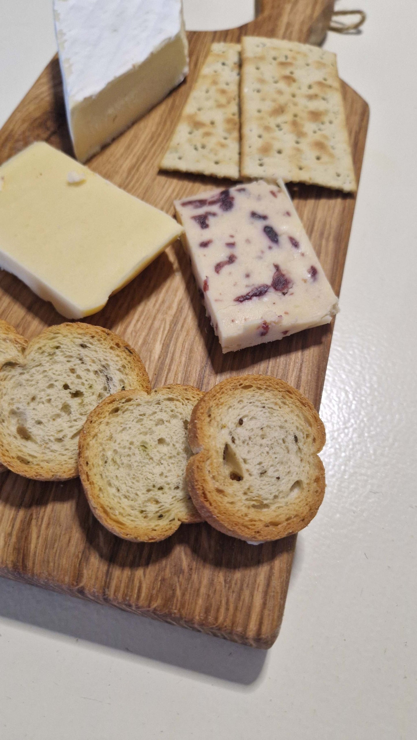 Handmade oak charcuterie board with assorted cheeses and crackers.