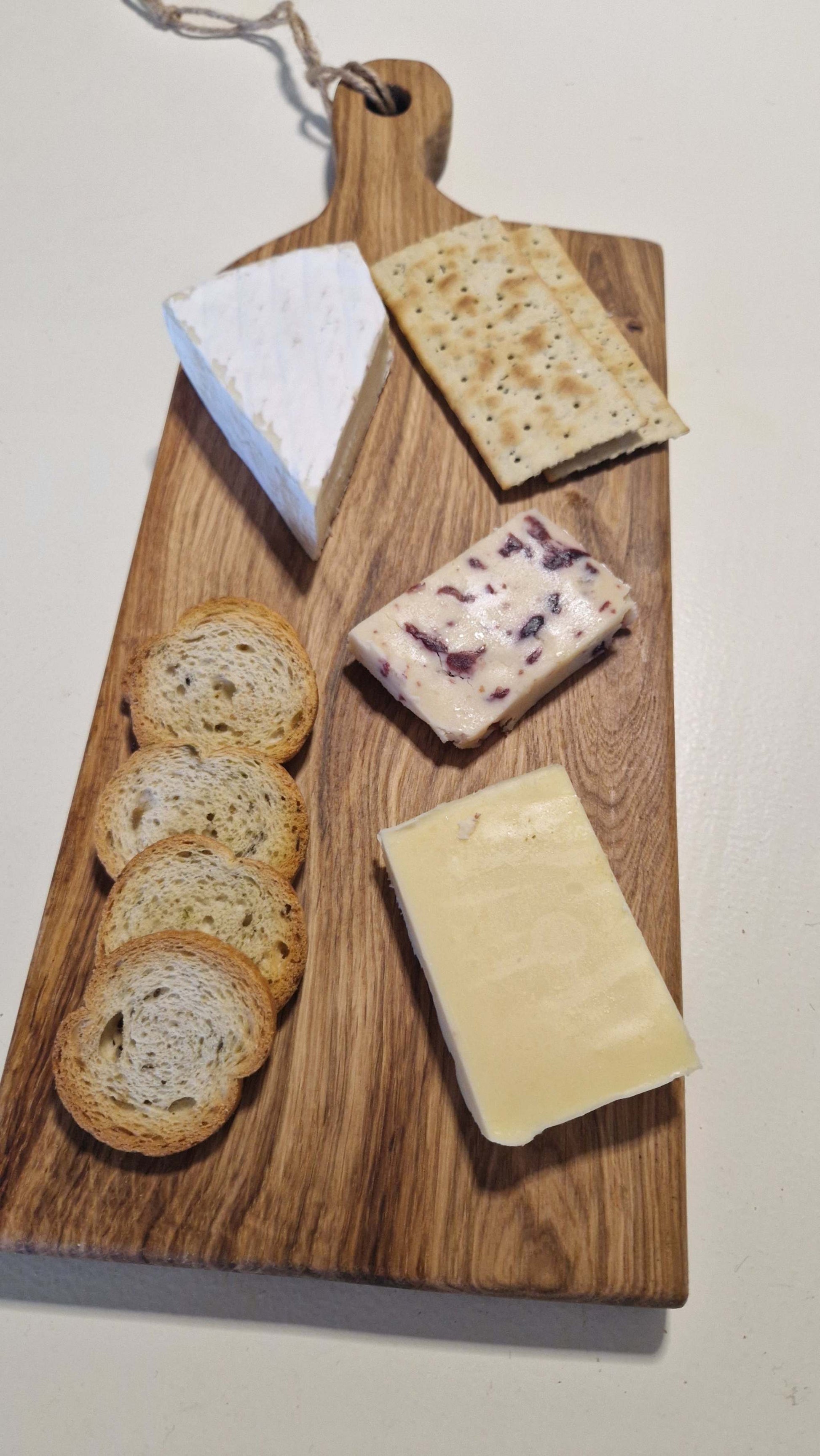Handmade oak charcuterie board with cheese and crackers.