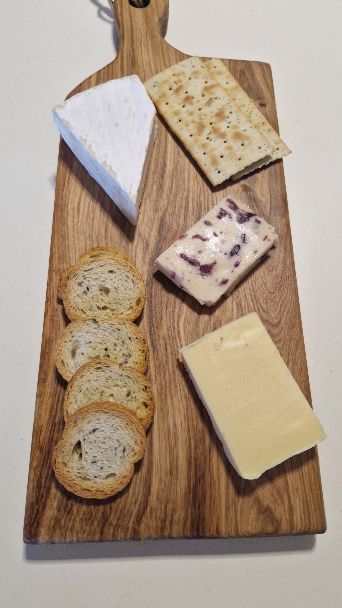 Handmade charcuterie board with assorted cheeses and crackers, crafted from premium oak wood.
