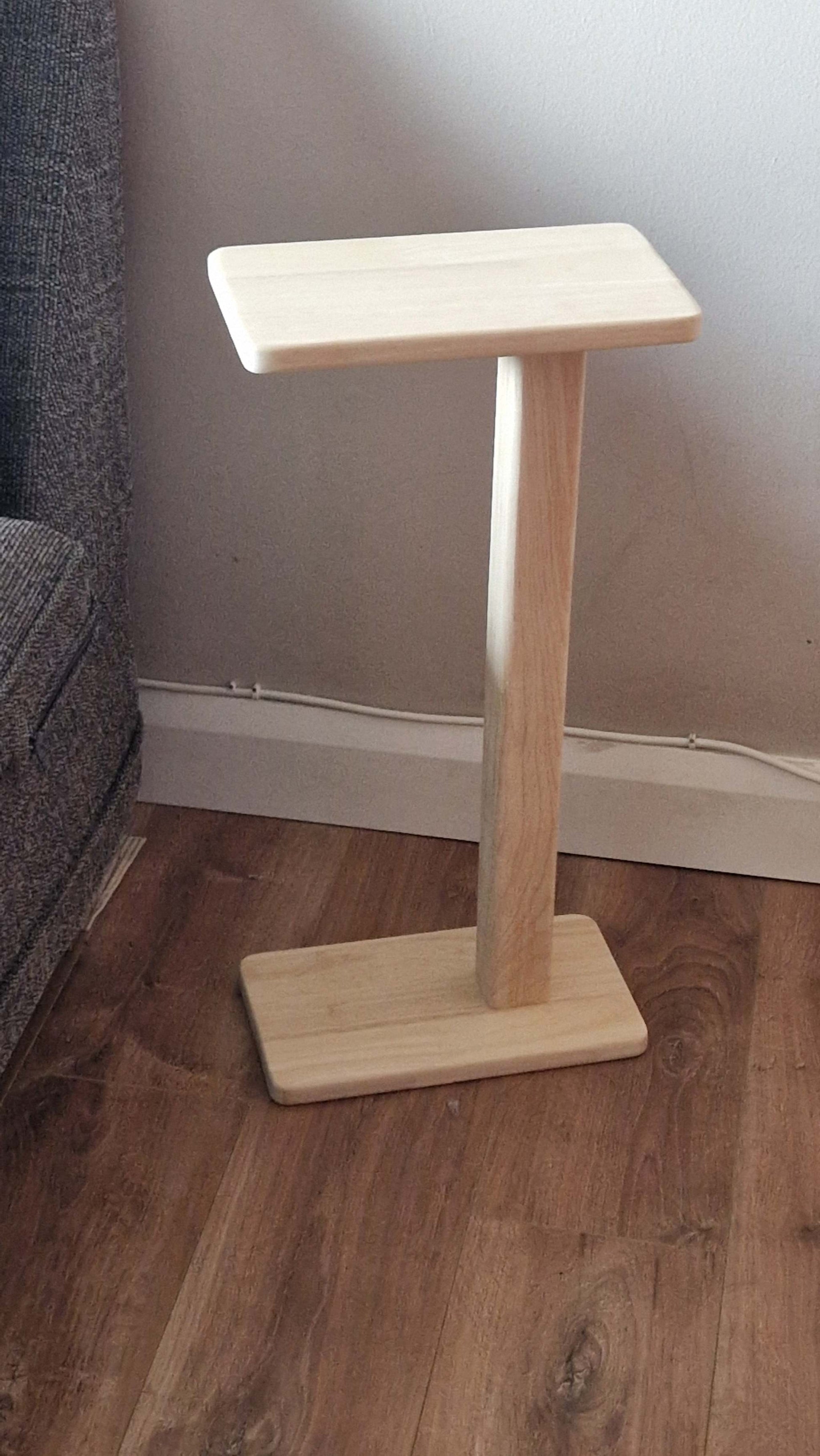 Handmade oak wooden couch table with sleek C-shape design on wooden floor.