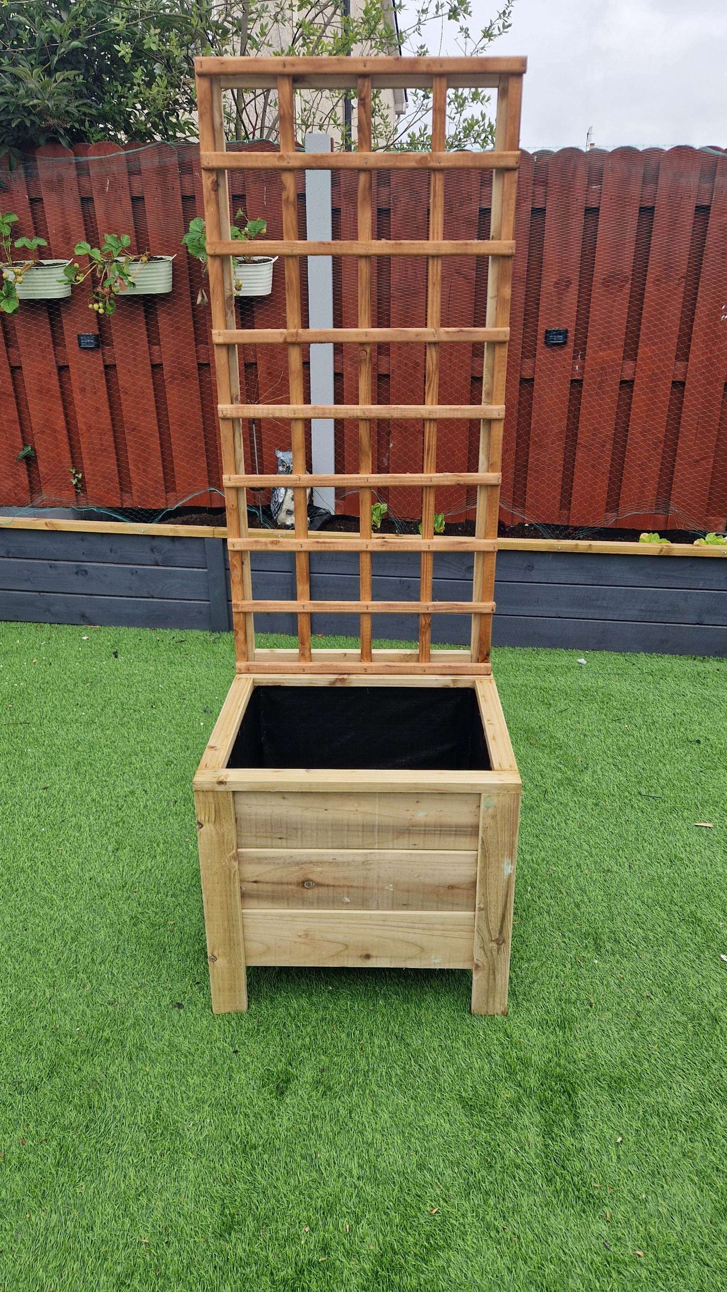 Handcrafted wooden planter with trellis on grass, ideal for climbing plants.