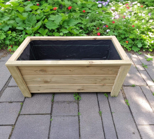 Handmade wooden planter on a patio surrounded by greenery.